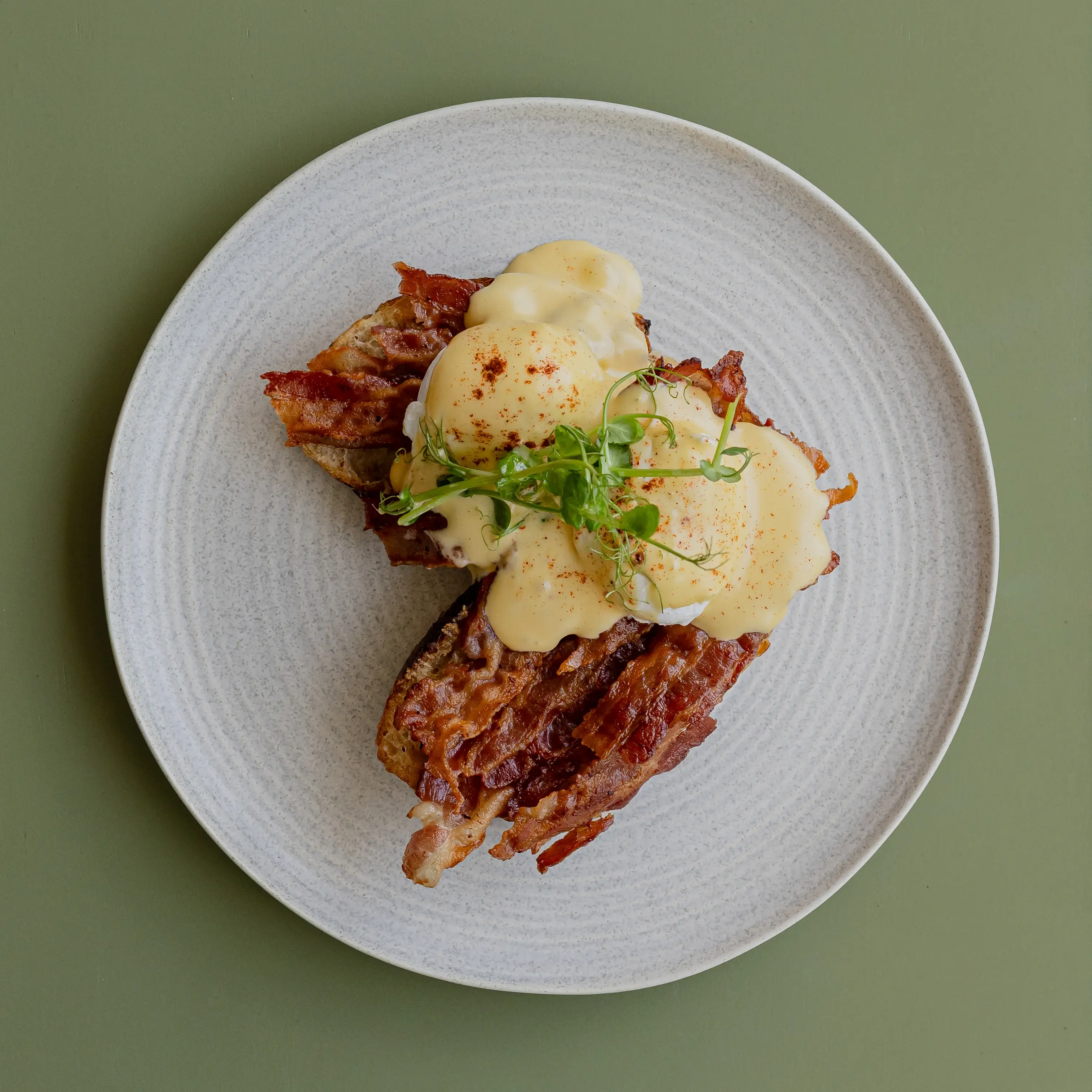 Eggs benny with smoked bacon, apple cider hollandaise, snow pea tendrils